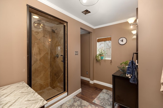 bathroom with a shower stall, baseboards, crown molding, and wood finished floors