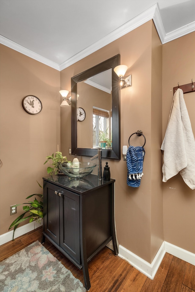 bathroom with crown molding, wood finished floors, and baseboards