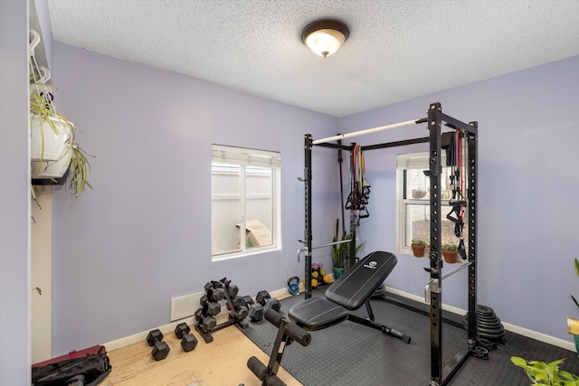 workout area with visible vents, baseboards, and a textured ceiling
