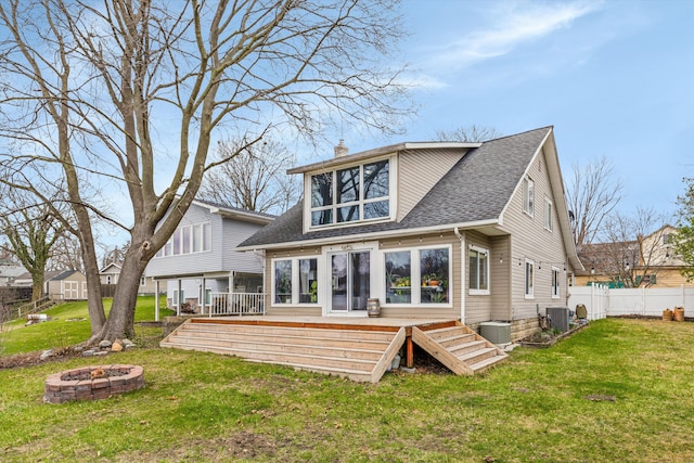 rear view of house with a wooden deck, a yard, an outdoor fire pit, a chimney, and central AC unit