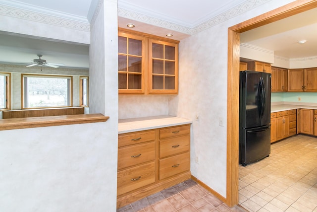 kitchen featuring ornamental molding, light countertops, freestanding refrigerator, and glass insert cabinets