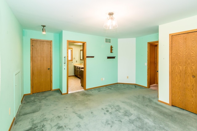 unfurnished bedroom with visible vents, baseboards, connected bathroom, and carpet floors