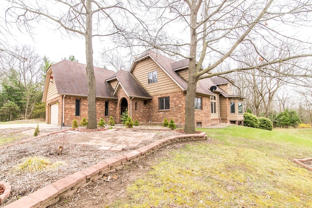 view of front of house with brick siding, a front yard, roof with shingles, and concrete driveway