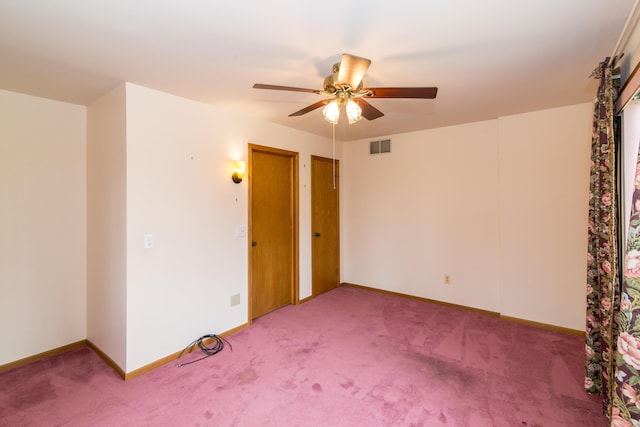 carpeted spare room featuring ceiling fan, baseboards, and visible vents