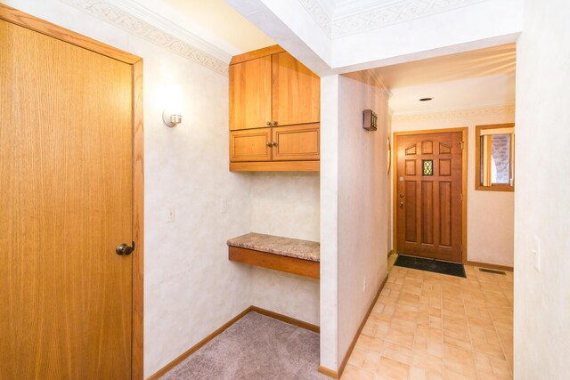 interior space with visible vents, baseboards, and ornamental molding