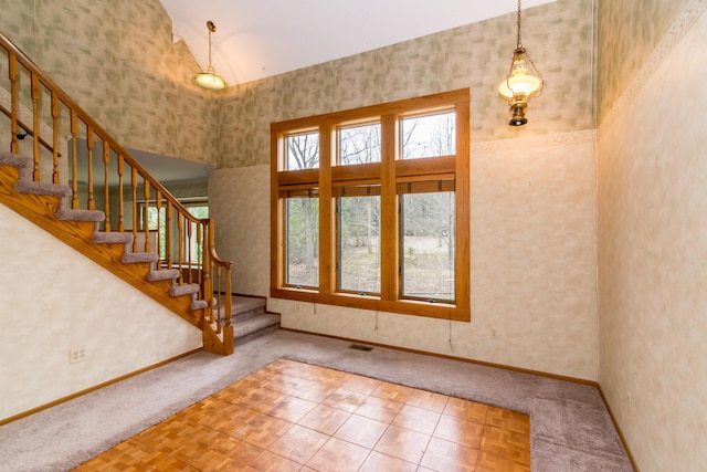 entryway with carpet floors, baseboards, visible vents, and stairway