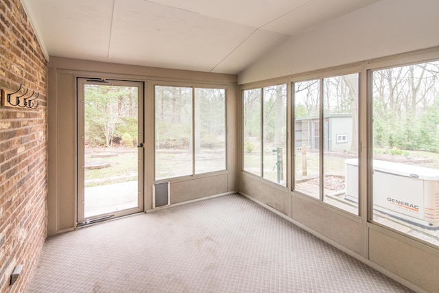 unfurnished sunroom featuring carpet floors, brick wall, and lofted ceiling