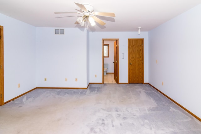 carpeted empty room with baseboards, a ceiling fan, and visible vents