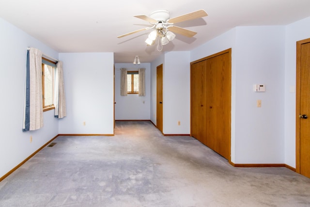 carpeted empty room with baseboards, a ceiling fan, and visible vents