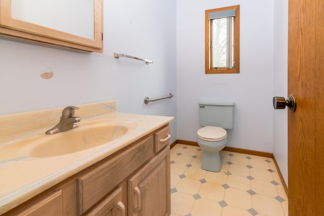 half bath with toilet, tile patterned floors, vanity, and baseboards