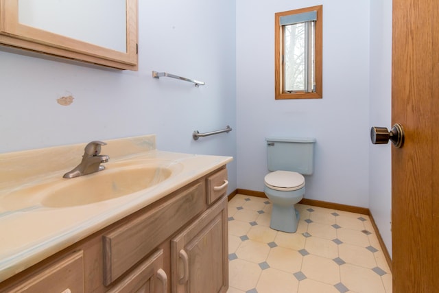 half bathroom featuring tile patterned floors, vanity, baseboards, and toilet