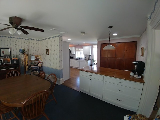 kitchen featuring ceiling fan, dark wood-type flooring, white cabinetry, hanging light fixtures, and wallpapered walls