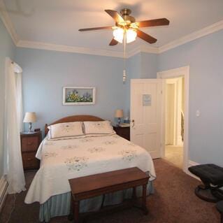 bedroom with carpet flooring, ornamental molding, and a ceiling fan
