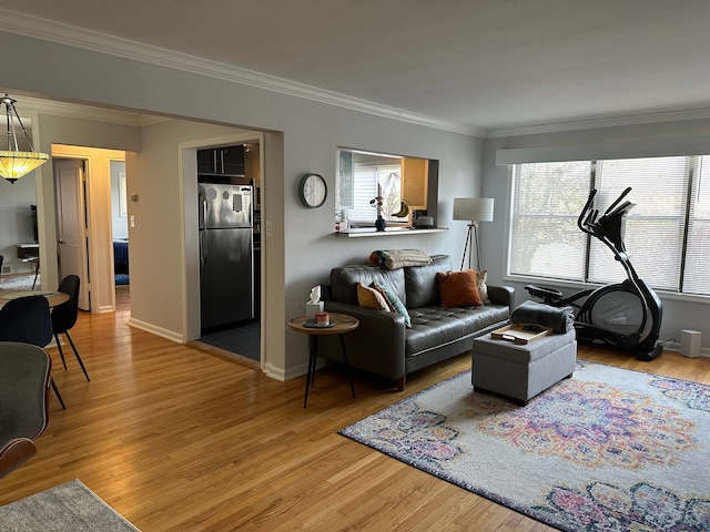 living room with crown molding, light wood-style flooring, and baseboards