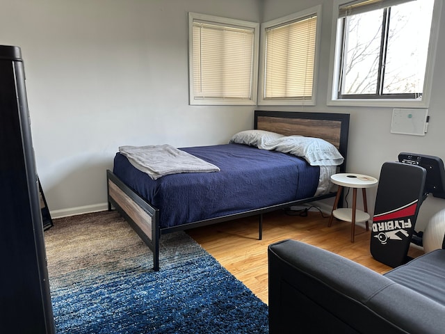 bedroom with freestanding refrigerator and wood finished floors