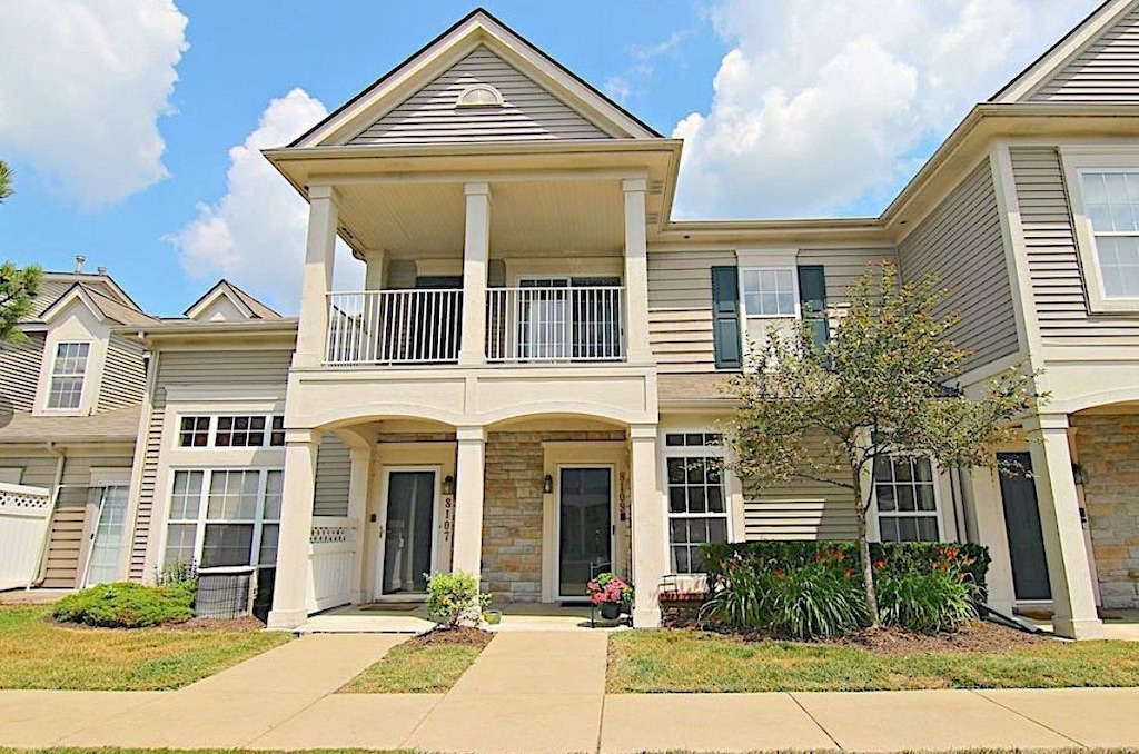 townhome / multi-family property with stone siding and a balcony