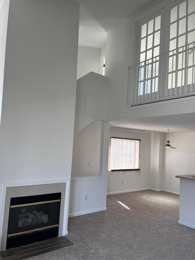 unfurnished living room featuring carpet flooring, a tiled fireplace, and baseboards