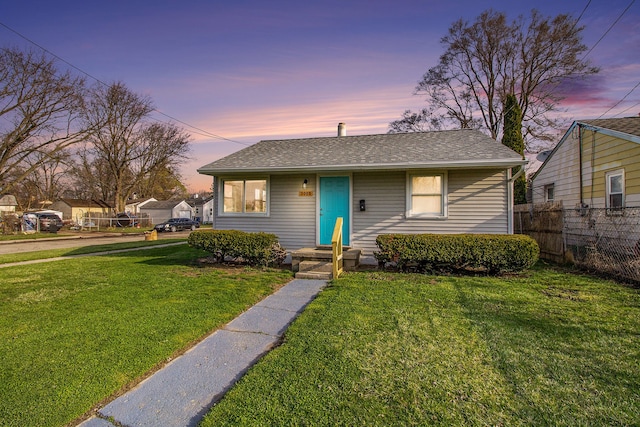 bungalow with a front yard, fence, and roof with shingles