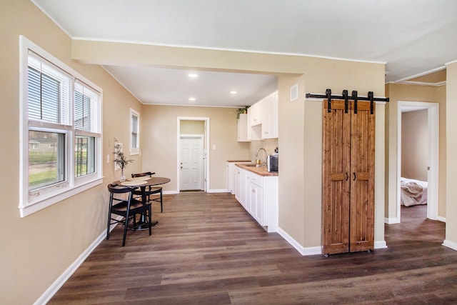 kitchen with a sink, ornamental molding, white cabinets, and dark wood-type flooring