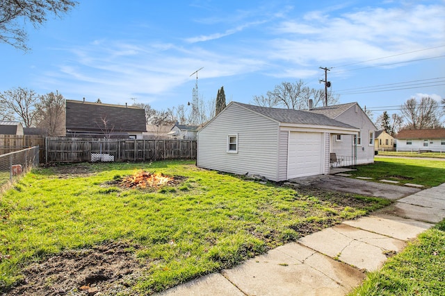 exterior space featuring an outdoor fire pit, driveway, fence, and a lawn