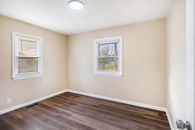 spare room featuring dark wood-style flooring, baseboards, and visible vents