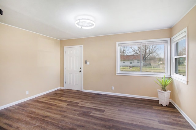 spare room featuring baseboards and dark wood-style floors