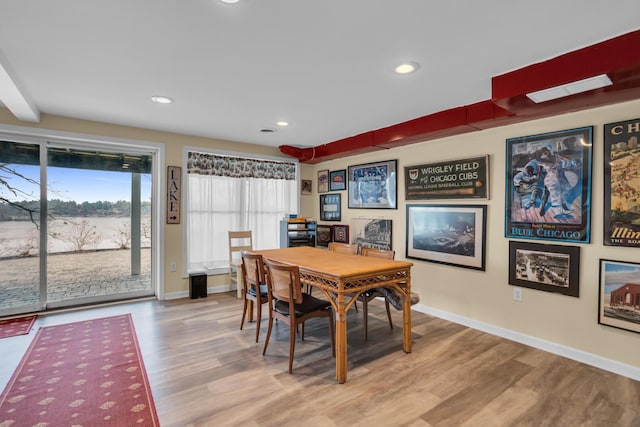 dining room featuring a water view, recessed lighting, light wood-type flooring, and baseboards