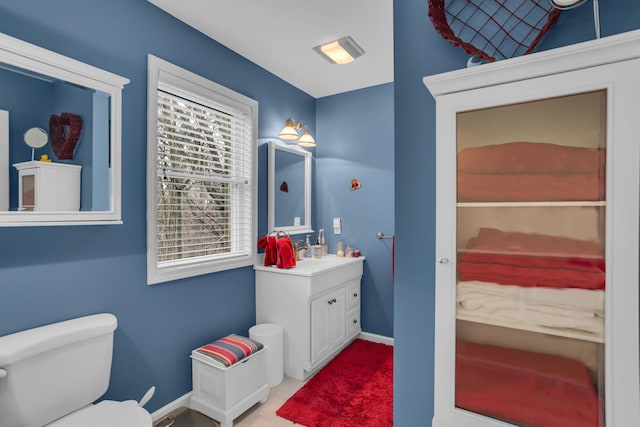bathroom with toilet, vanity, and baseboards