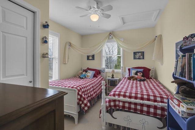 bedroom with a ceiling fan, attic access, multiple windows, and carpet flooring