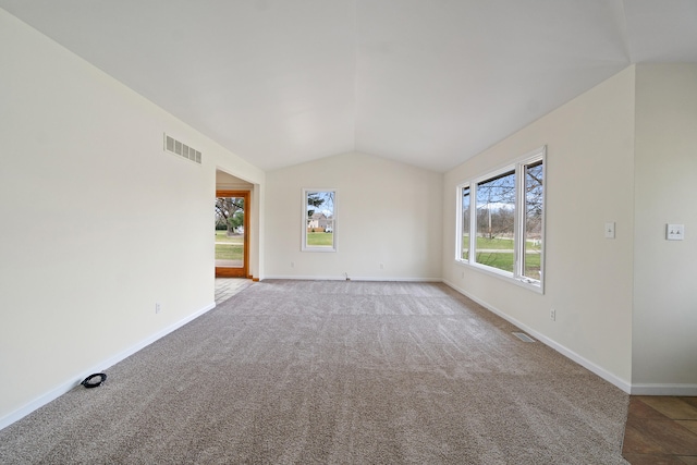 empty room featuring carpet flooring, visible vents, baseboards, and vaulted ceiling