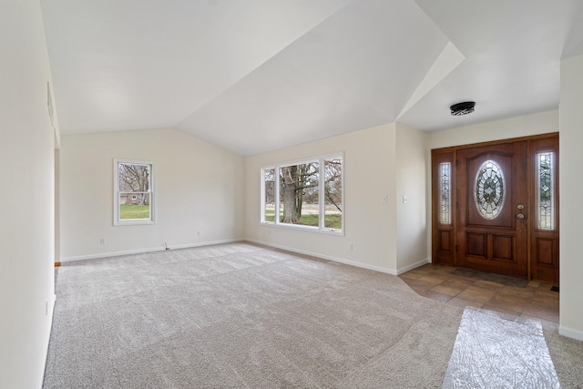 carpeted foyer featuring baseboards and lofted ceiling