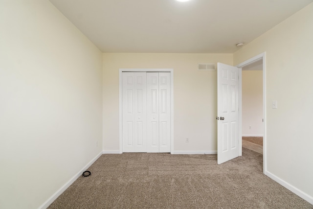 unfurnished bedroom with a closet, carpet flooring, baseboards, and visible vents