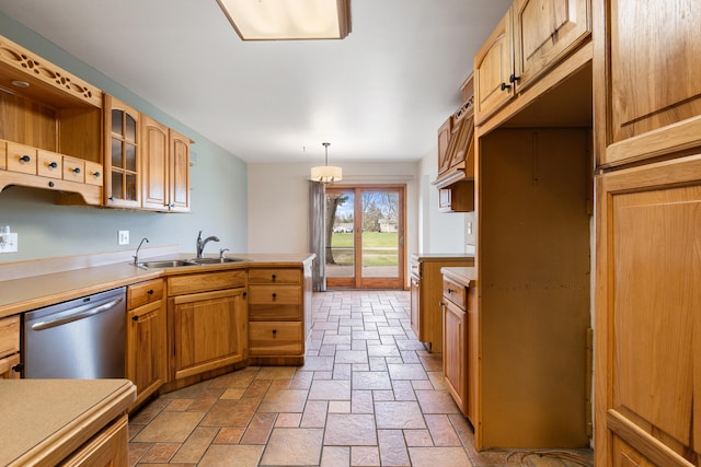 kitchen featuring glass insert cabinets, dishwasher, a sink, a peninsula, and stone tile floors