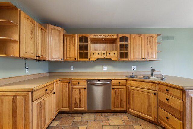 kitchen featuring light countertops, open shelves, stone finish floor, stainless steel dishwasher, and a sink