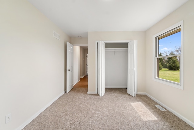 unfurnished bedroom with visible vents, baseboards, a closet, and light colored carpet