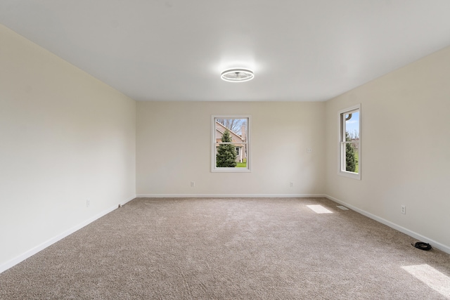 unfurnished room with a wealth of natural light, light carpet, and baseboards