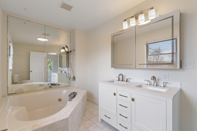 bathroom featuring a whirlpool tub, visible vents, a sink, and toilet