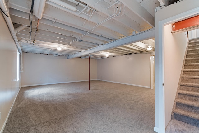 finished basement with carpet flooring, baseboards, and stairway