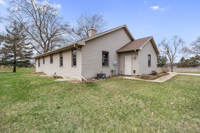 exterior space with central AC unit, a front lawn, and a chimney