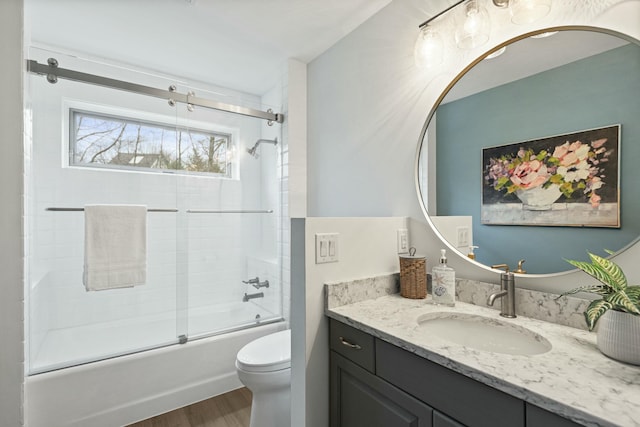 bathroom featuring toilet, shower / bath combination with glass door, wood finished floors, and vanity