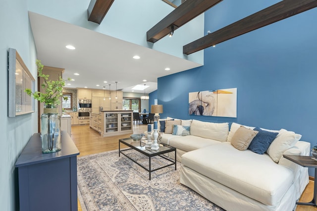living room with beamed ceiling, light wood-style flooring, and recessed lighting