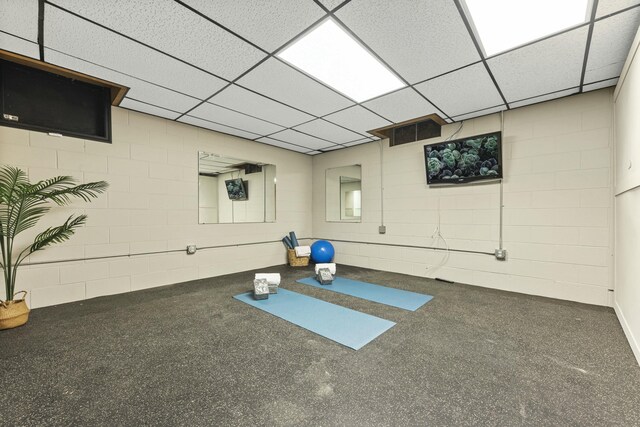 workout area featuring a drop ceiling, visible vents, and concrete block wall