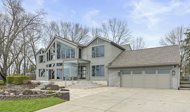 view of front facade featuring an attached garage, driveway, and roof with shingles