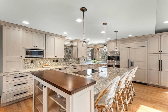 kitchen featuring light wood-style flooring, built in appliances, backsplash, and a spacious island