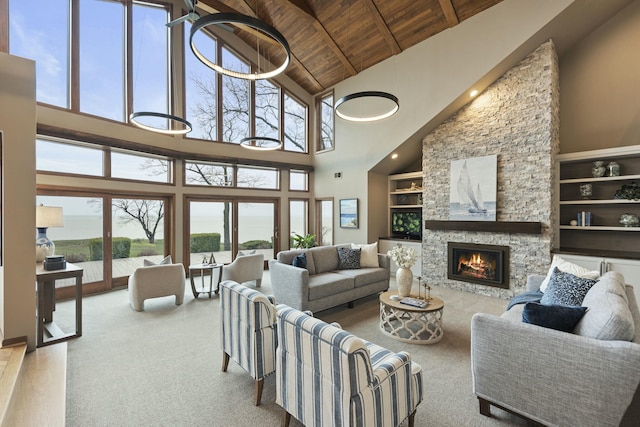 living area featuring high vaulted ceiling, a stone fireplace, wood ceiling, built in shelves, and beam ceiling