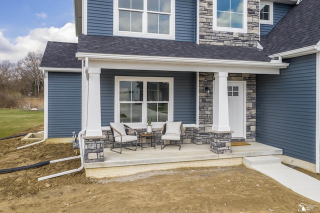 property entrance with a porch, stone siding, and a shingled roof