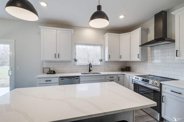 kitchen featuring tasteful backsplash, wall chimney exhaust hood, a sink, and appliances with stainless steel finishes
