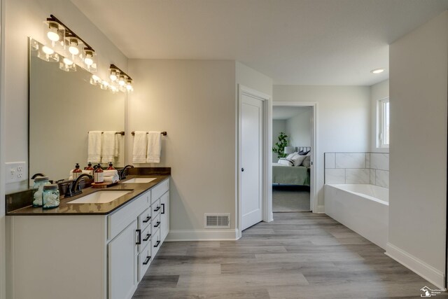 bathroom featuring a sink, visible vents, double vanity, and wood finished floors