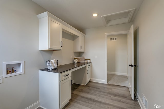 interior space featuring light wood-style floors, hookup for a washing machine, visible vents, baseboards, and cabinet space