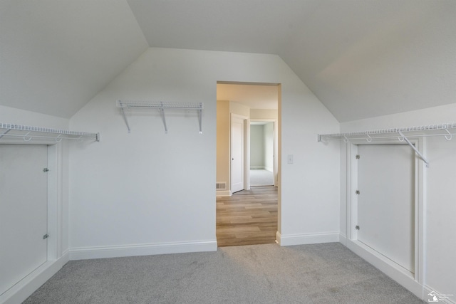 spacious closet with visible vents, light carpet, and lofted ceiling